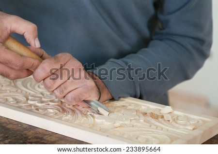 Man Sculptor  sculpting wood to create a wooden flora design.