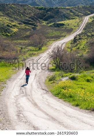 Unrecognized Teenage girl running in the countryside remote empty  road.