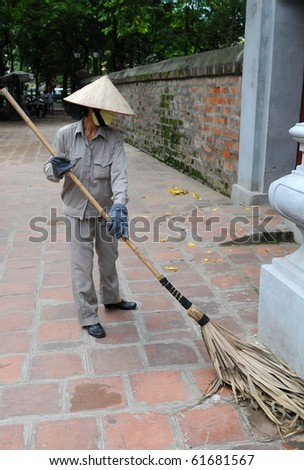 Vietnamese sweeper woman cleaning the pavement and road