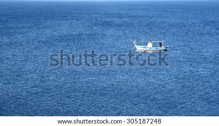 An unrecognized fisherman in a lonely wooden fishing Boat on a calm blue sea in the Mediterranean. Picture taken at Protaras area in Cyprus