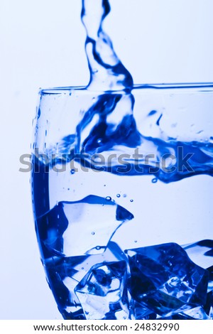 Blue Glass with Splashing water. Coolness Drink