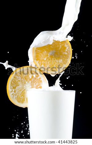 Splashing milk with orange on black background