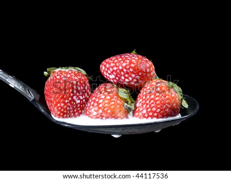 Fresh strawberry in spoon with creative milk splashing