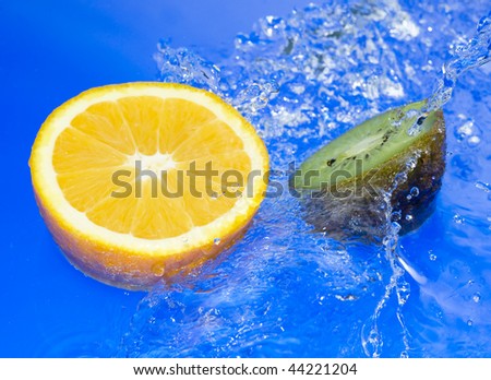 Orange and kiwi with splashing water. Tropical citrus fruit
