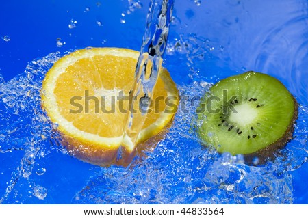 Orange and kiwi with splashing water. Tropical citrus fruit