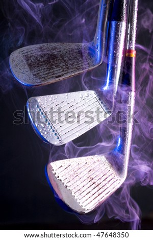 Old golf clubs with smoke on black background