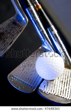 Old golf clubs with  ball on black background