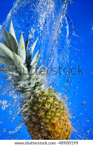 Pineapple with splashing water on blue background