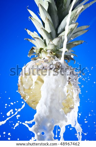 Pineapple with splashing milk on blue background