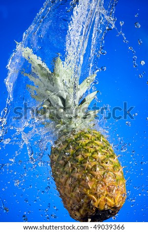 Pineapple with splashing water on blue background
