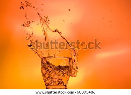 Whisky and ice. Splashing scotch on brown background