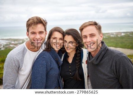 Portrait of four friends posing together happily outdoors on a nature trail