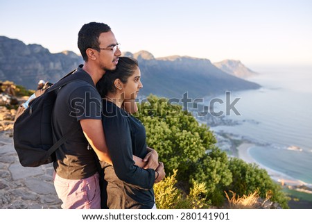 Loving young Indian couple taking in the view while on a mountain nature hike
