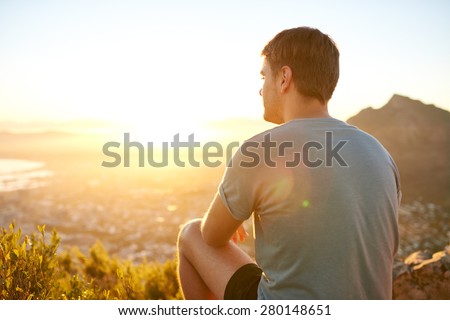 Rear view of a young guy resting on a nature trail watching the sunrise
