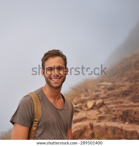 Portrait of a happy young hiker pausing on a mountain walk on a rocky nature trail
