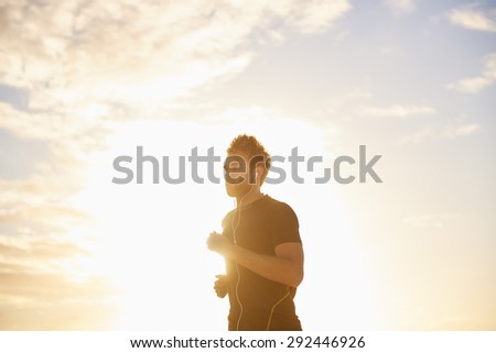Healthy young man jogging early in the morning with gentle sun flare