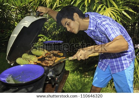 asian man cooking on an outdoor grill