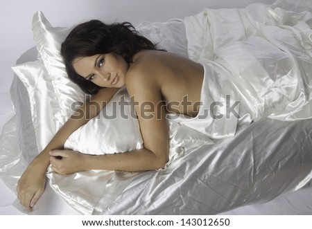 beautiful woman on white satin sheets