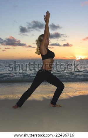 A forty year old woman doing yoga at sunrise on the beach in Hawaii
