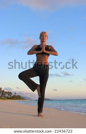 A forty year old woman doing yoga at sunrise on the beach in Hawaii