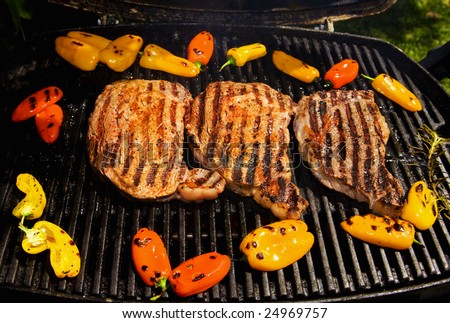 ribeye steaks cook on the bar-b-que grill with baby bell peppers