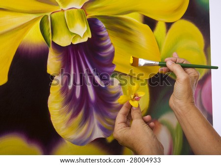 Close up of a female artist\'s hands painting dendrobium orchids on canvas in her studio