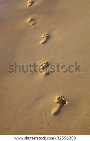 Footprints in the sand on a beach in Hawaii in the late afternoon