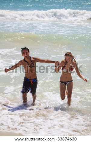 A young couple runs out of the ocean at Kailua Beach, Hawaii