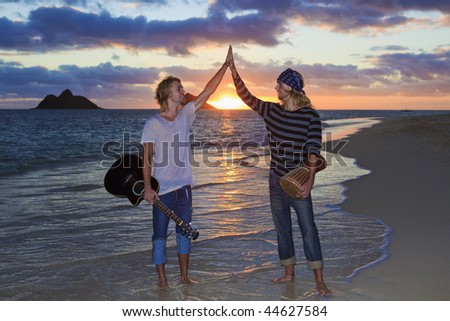 twin brothers with their guitar and drum at sunrise on the beach in hawaii