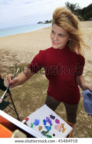 female artist painting outdoors at a beach