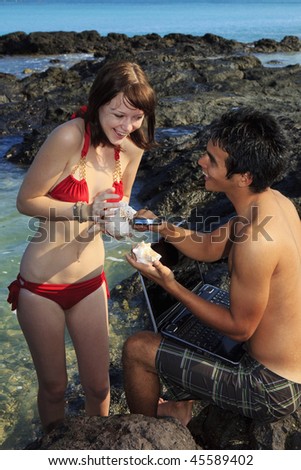 couple at hawaiian tidepools with computer and sea shells