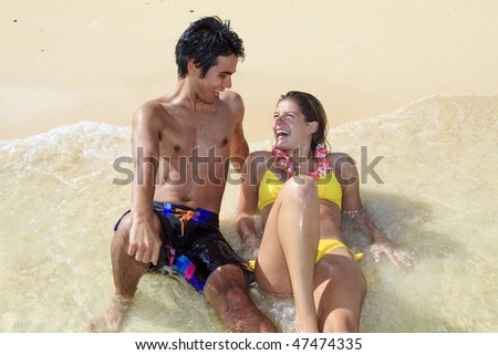 pacific island man and young woman at water\'s edge on a hawaii beach