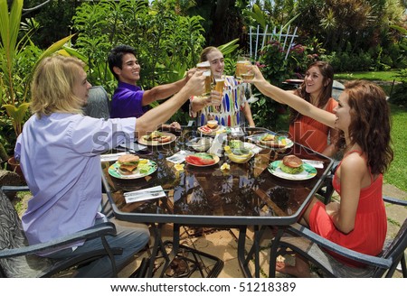 friends at a backyard bar-b-que in hawaii raising their glasses in a toast