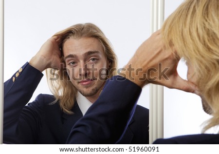 young man runs his hand through his hair in a mirror