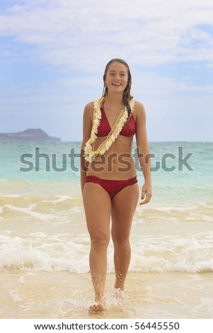 pretty teenage girl walk out of the ocean with a flower lei at kailua beach