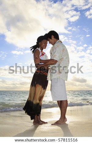 young mixed race couple at the beach in hawaii at sunrise