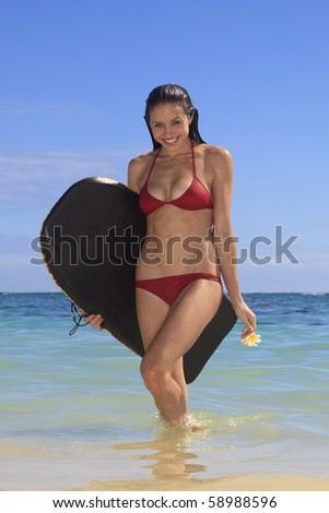 beautiful young woman at the beach in hawaii with her boogie board