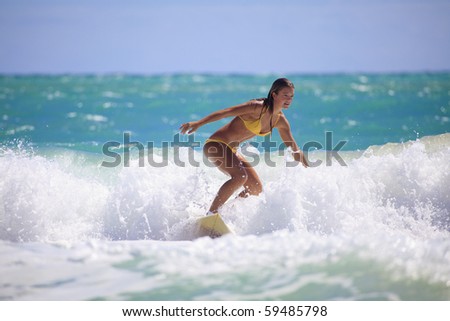 teenage girl in a yellow bikini surfing in Hawaii teenage girl in a yellow bikini surfing in Hawaii