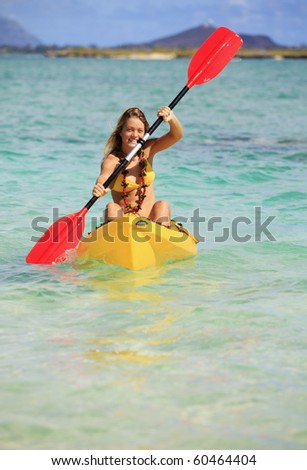 pretty teenage girl with her kayak paddling in the warm Pacific waters of Hawaii