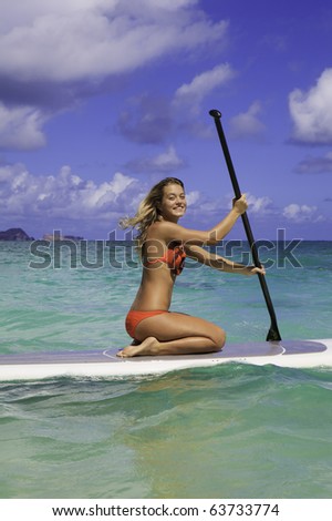 girl in bikini on a  stand up paddle board in hawaii