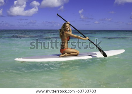 girl in bikini on a  stand uppaddle board in hawaii