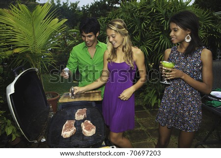 three friends at a barbecue party in their tropical garden in hawaii