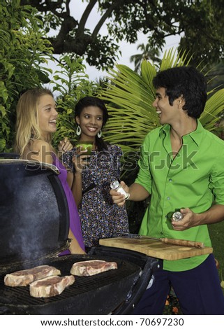 three friends at a barbecue party in their tropical garden in hawaii