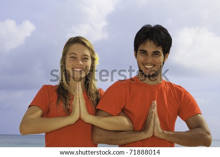 young couple doing yoga, exercise , and meditations on a hawaii beach