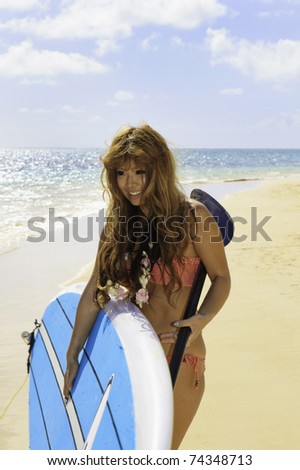 young japanese woman in a bikini with her paddle board by the ocean in Hawaii