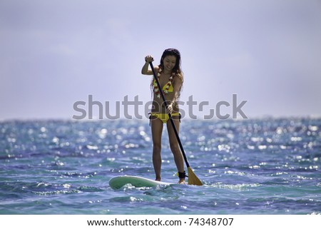 young japanese woman in a bikini with her paddle board in the ocean in Hawaii
