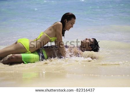 couple playing at the water\'s edge on a hawaii beach