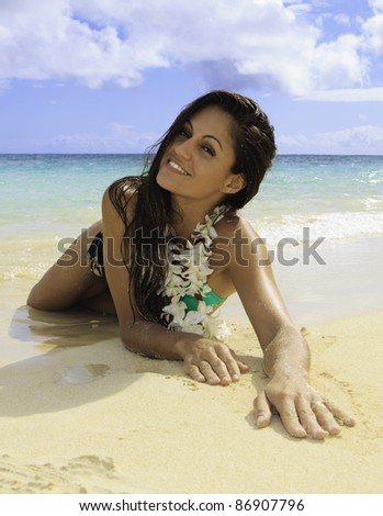 beautiful girl lounging on the sand at water\'s edge in lanikai