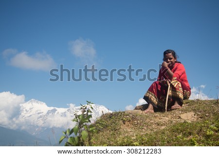 Nepal - Circa October 2014: Nepalese woman wears traditional clothes sitting down on the mountain