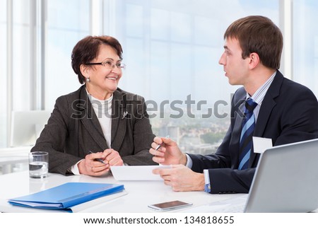 Manager advises the elderly woman in the office
